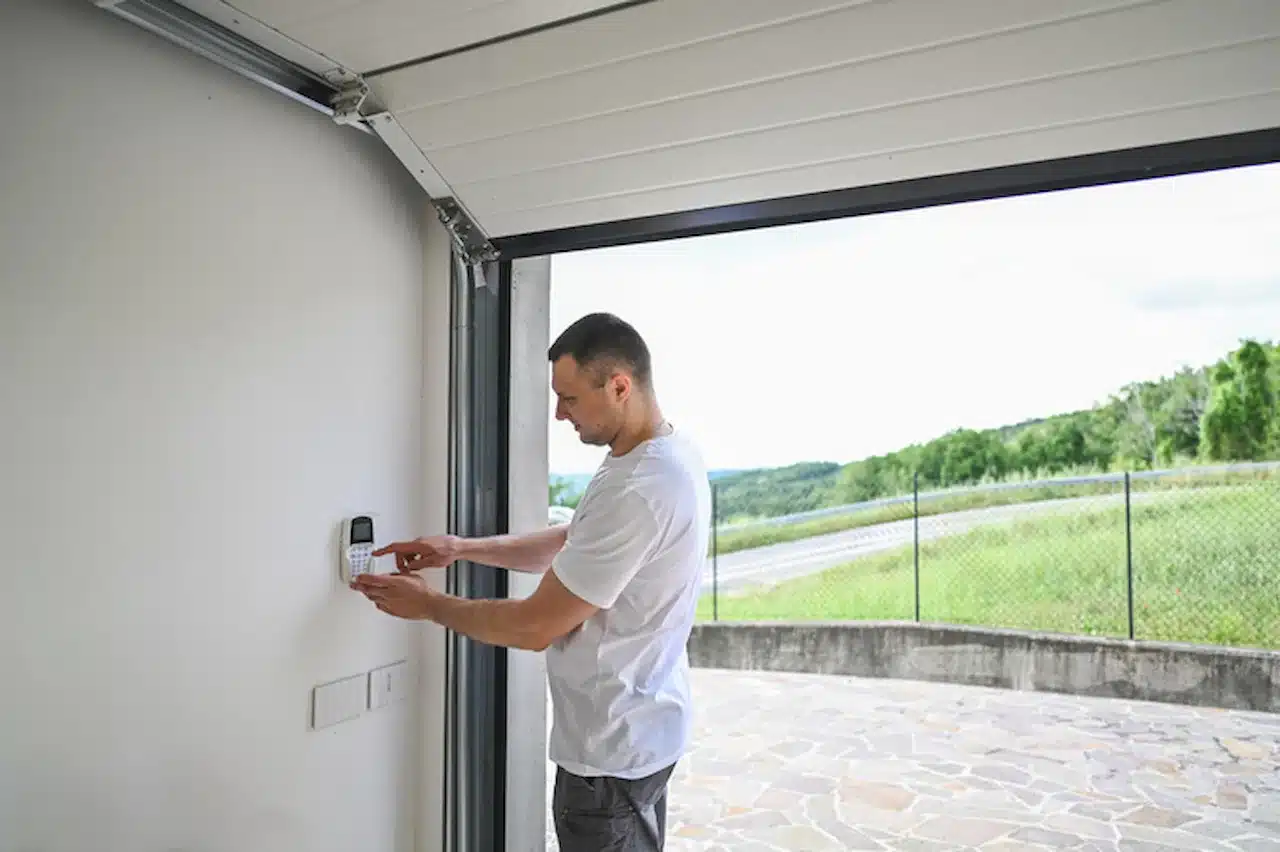 Man entering security code on a garage door keypad control panel.